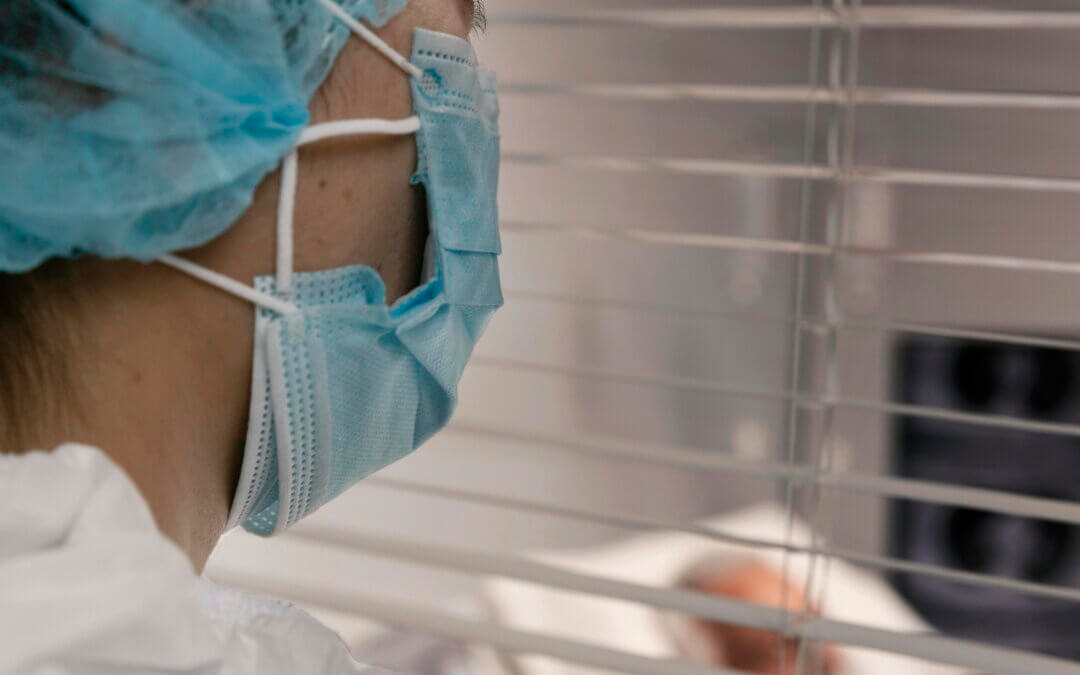 Soignante en tenue professionnelle regardant par une vitre, en réflexion
